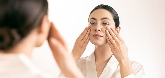 image shows a woman gently massaging her face