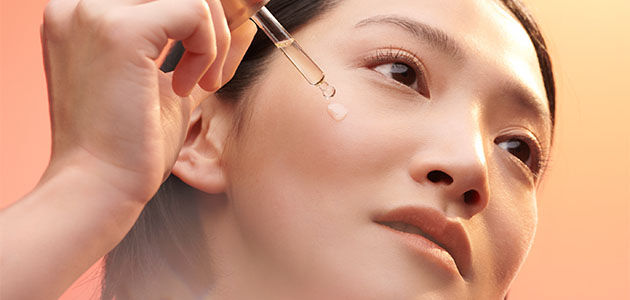 This image shows a woman applying the L'OCCITANE Immortelle Divine Serum