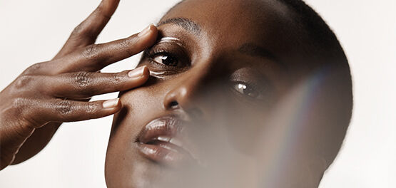 The image shows the face of a woman touching her under eye