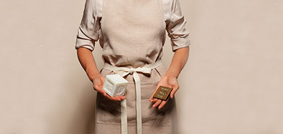 Craftswoman holding L'OCCITANE Bonne M&egrave;re Soap Bar and stamp used in the manufacturing process, Savon de Marseille, Provence