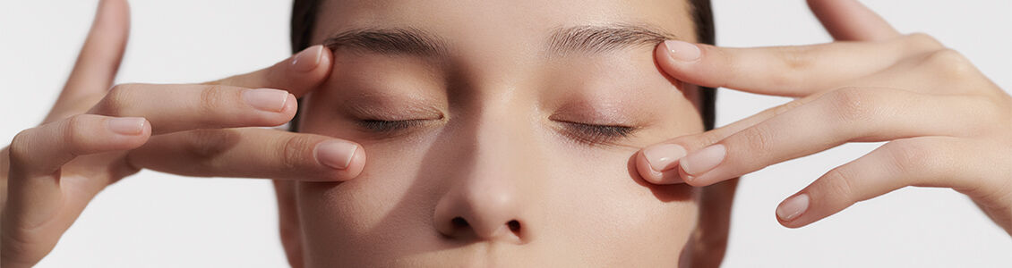 Image shows woman gently touching her under eye