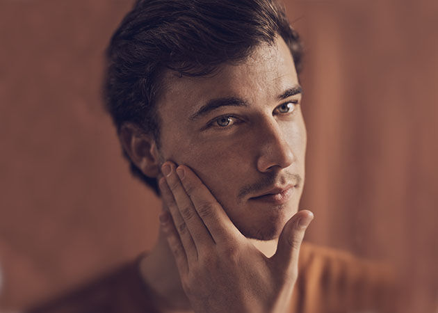 The image shows a man gently touching his face