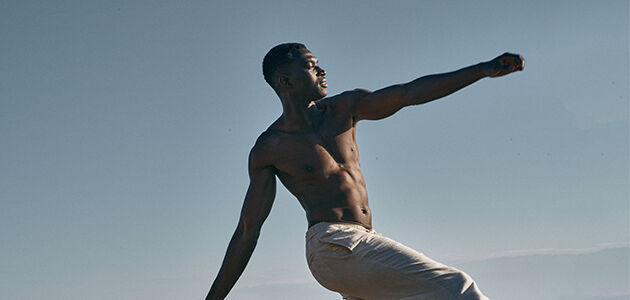 Man practising yoga on beach 