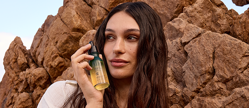 The image shows a woman holding the L'OCCITANE Anti-hair loss serum