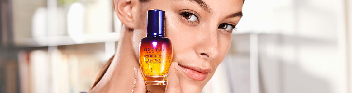 Woman holding L'OCCITANE Immortelle Reset Overnight Serum