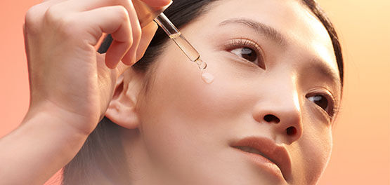 This image shows a woman applying the L'OCCITANE Immortelle Divine Serum