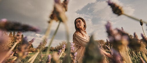 Woman walking through Lavender fields in Provence, L'OCCITANE Protected Destination of Origin Organic Fine Lavender