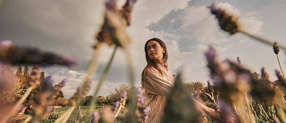 Woman walking through Lavender fields in Provence, L'OCCITANE Protected Destination of Origin Organic Fine Lavender