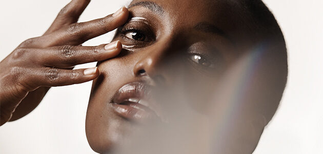 The image shows the face of a woman touching her under eye